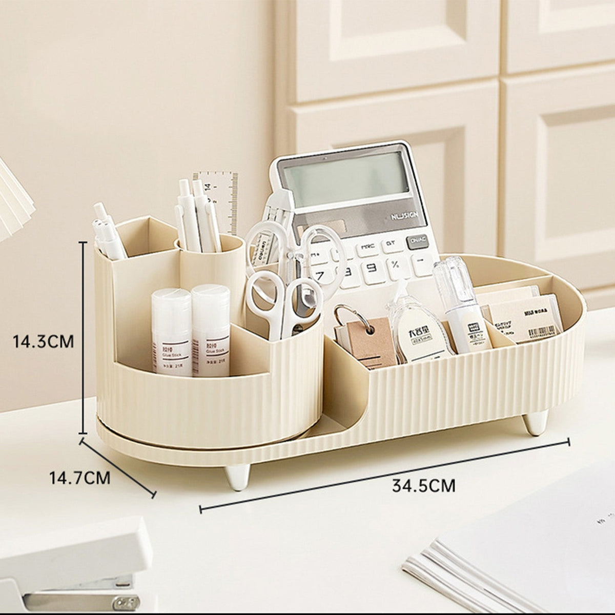A cream-colored ribbed desktop organizer with multiple compartments, shown holding office supplies including a calculator, pens, scissors, and small bottles. White dimension lines and text overlay indicate its measurements: 14.