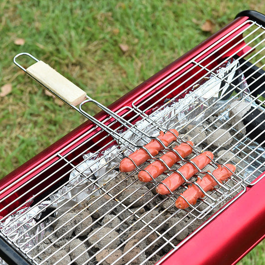 Hot dogs on a grill with a red handle against a grassy background