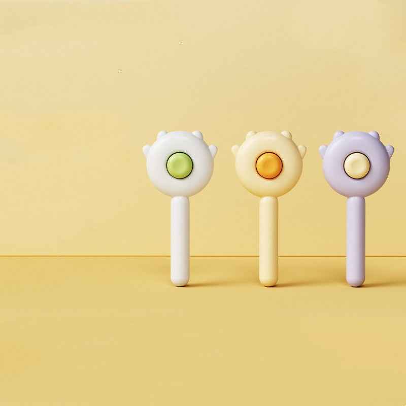 Three colorful baby rattles on a yellow background