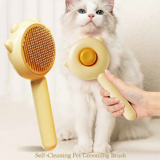 Person holding a yellow pet grooming brush next to a white cat