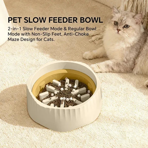 A cat slow feeder bowl for cats placed on a beige carpet next to a fluffy cream-colored cat. The bowl has a textured off-white exterior, a gold interior, and white non-slip feet around a bed of cat food.