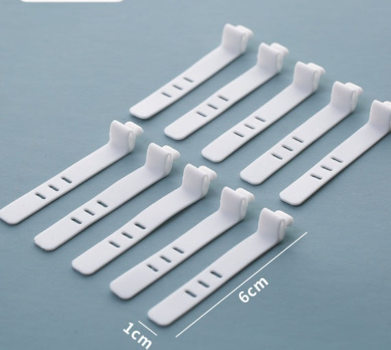 Ten small white plastic fastening clips arranged on a light blue-gray background, with overlaid dimension lines and text showing 6 cm length and 1 cm width.