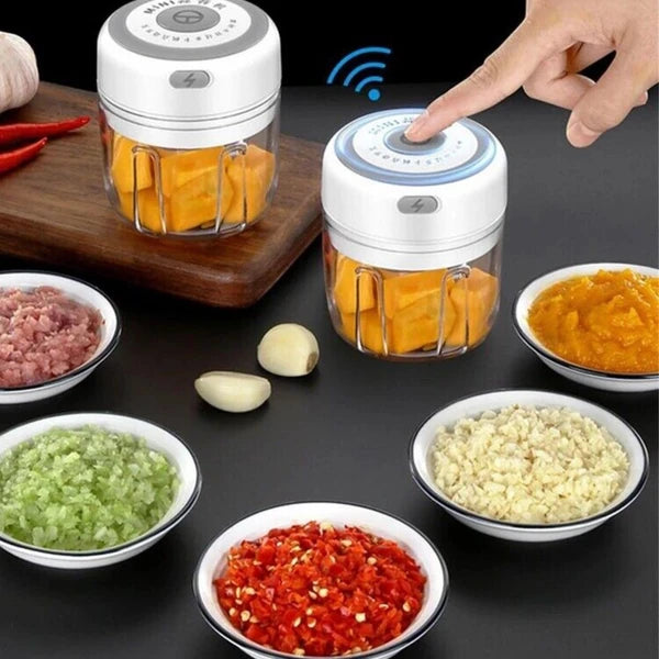 Small food chopper with chopped vegetables on a dark surface with small bowls of ingredients.