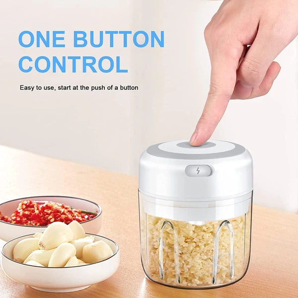 Handheld food chopper with one button control on a kitchen counter, surrounded by ingredients.