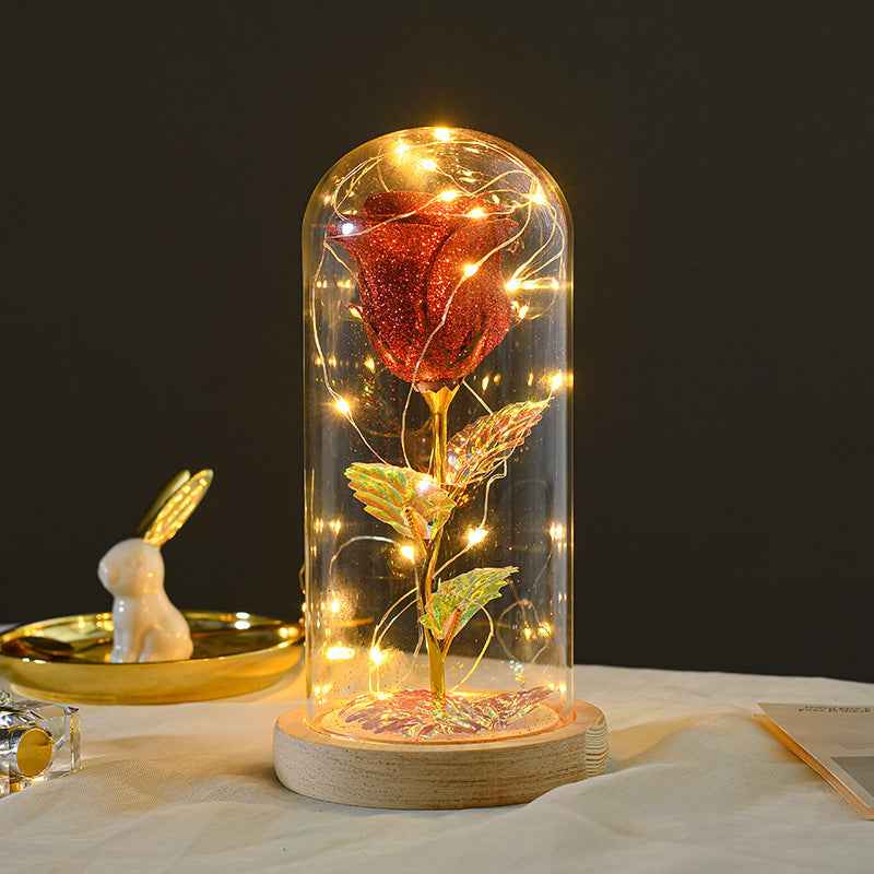 Decorative rose inside a glass dome with lights on a dark background