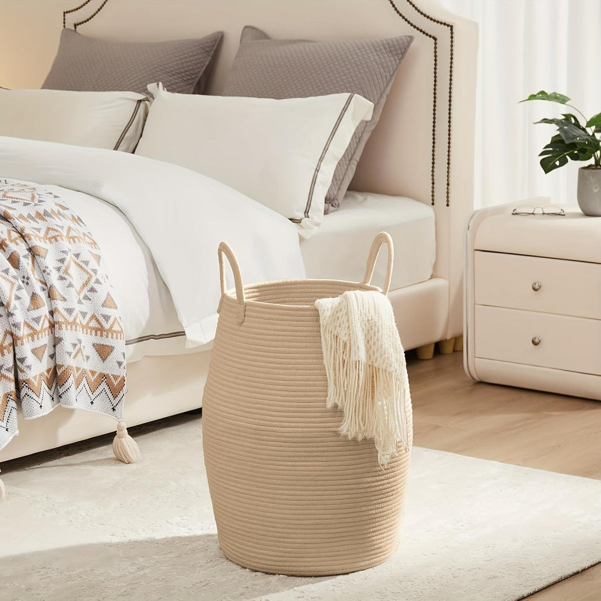 Beige woven basket with a blanket on a bed in a bedroom setting