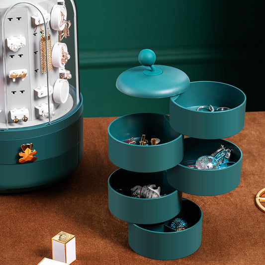 Teal jewelry organizer with multiple tiers filled with earrings on a brown surface.