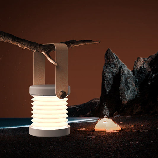 Collapsible lanterns on a natural setting with rocks and a branch.