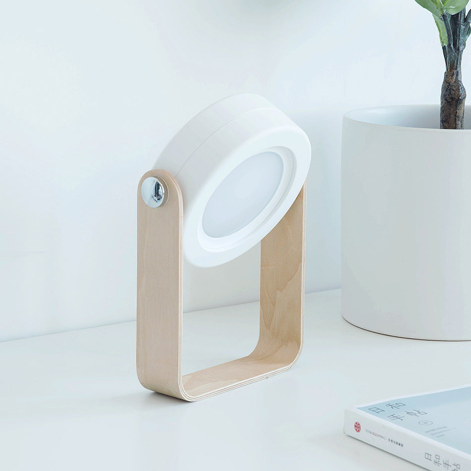 Modern table lamp with wooden base and white shade on a light surface.