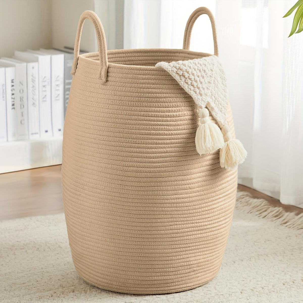 Beige woven laundry basket with a white towel draped over it on a light wooden floor.