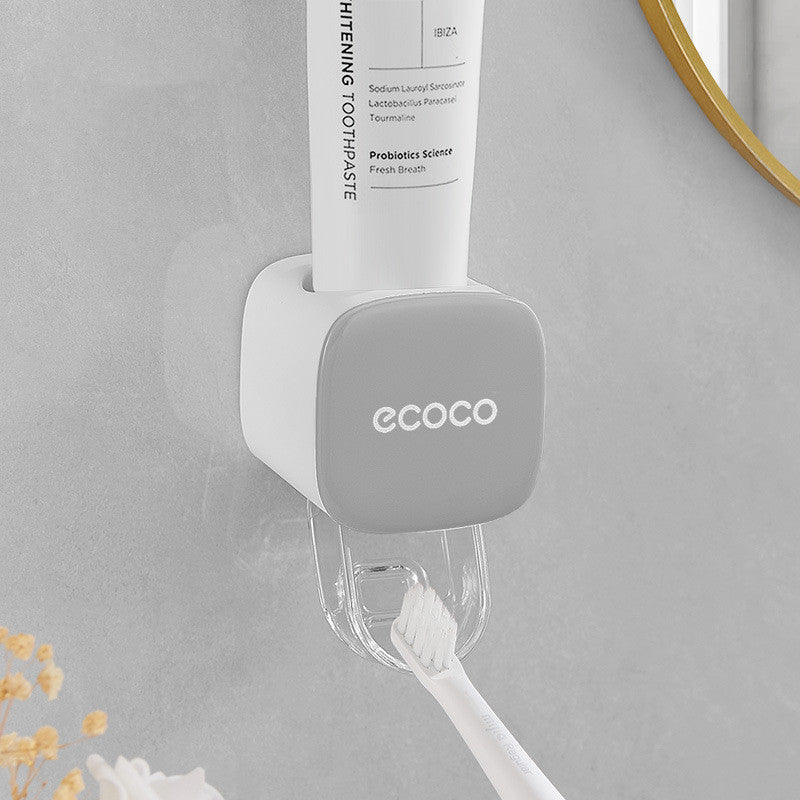 Toothpaste and toothbrush holder with 'ecoco' branding on a gray wall.