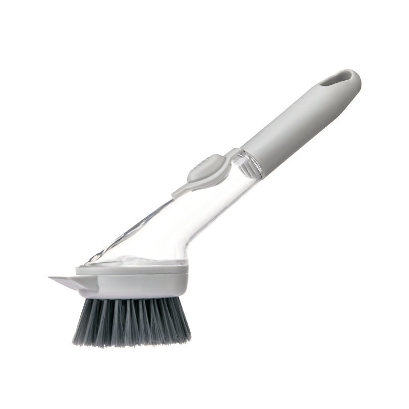 A kitchen cleaning brush with a white plastic handle, clear plastic body, dark gray bristles, and a small white scraper attachment, shown on a plain white background.