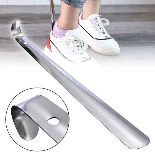 Metal shoe shine tool on a wooden floor with a person wearing white sneakers.