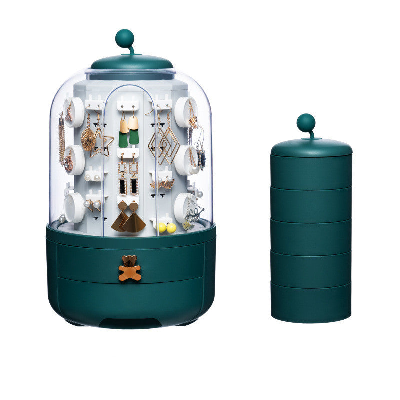 Green cylindrical jar with a clear top containing small figurines on a white background