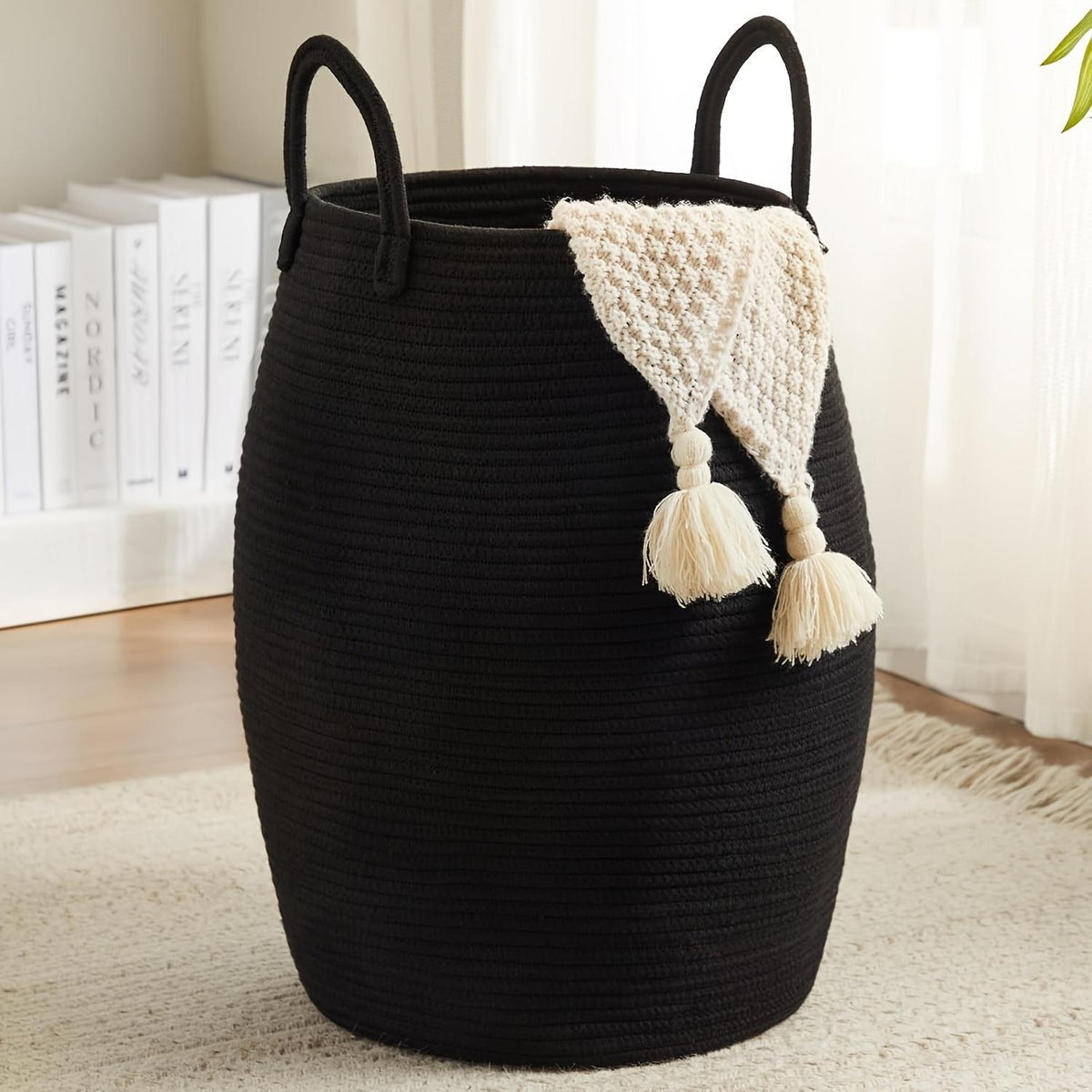 Black woven basket with handles and a decorative white item on a light-colored floor.