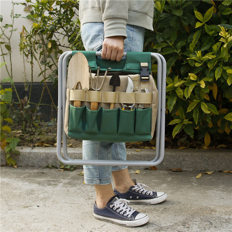 Person holding a green tool bag with gardening tools against a garden background