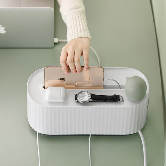 White charging station with phone, watch, and other items on a light green surface.