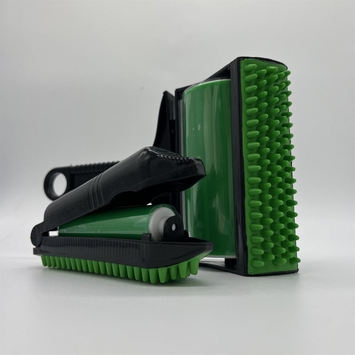 A green and black dual-sided cleaning brush roller set, featuring one side with dense green bristles and the other with a green textured scrubber pad, shown on a light gray background.