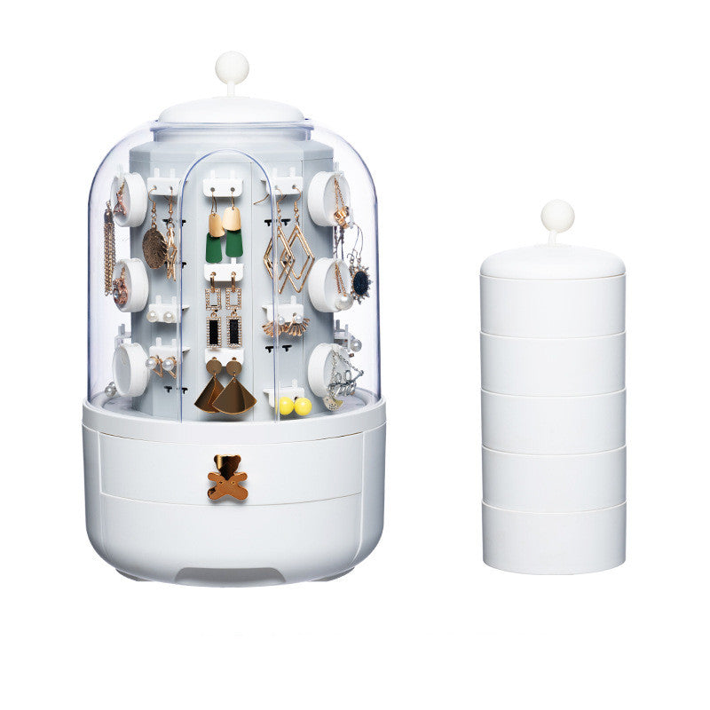Jewelry organizer with transparent lid displaying earrings and necklaces, next to a cylindrical white container on a white background.
