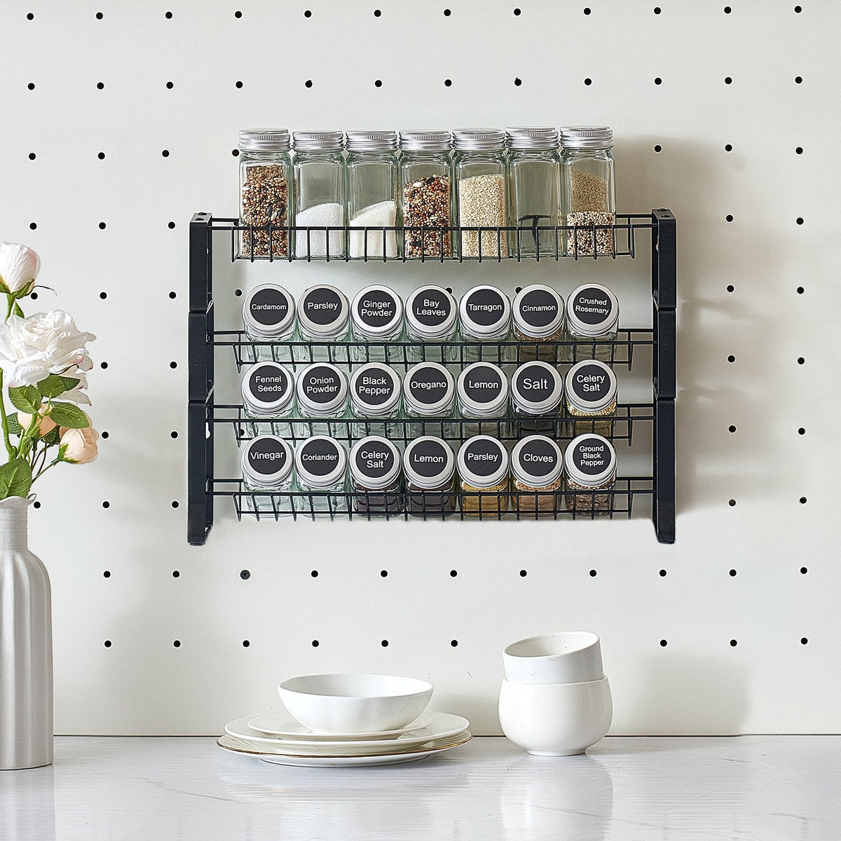 Spice rack with labeled jars on a pegboard wall, with decorative elements like flowers and bowls below.